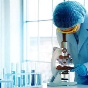 Scientist wearing PPC looking through a microscope in a life sciences lab