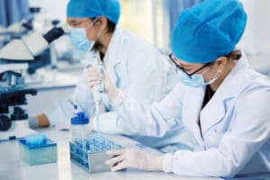 A stock image showing two scientists wearing PPC and working in a laboratory.