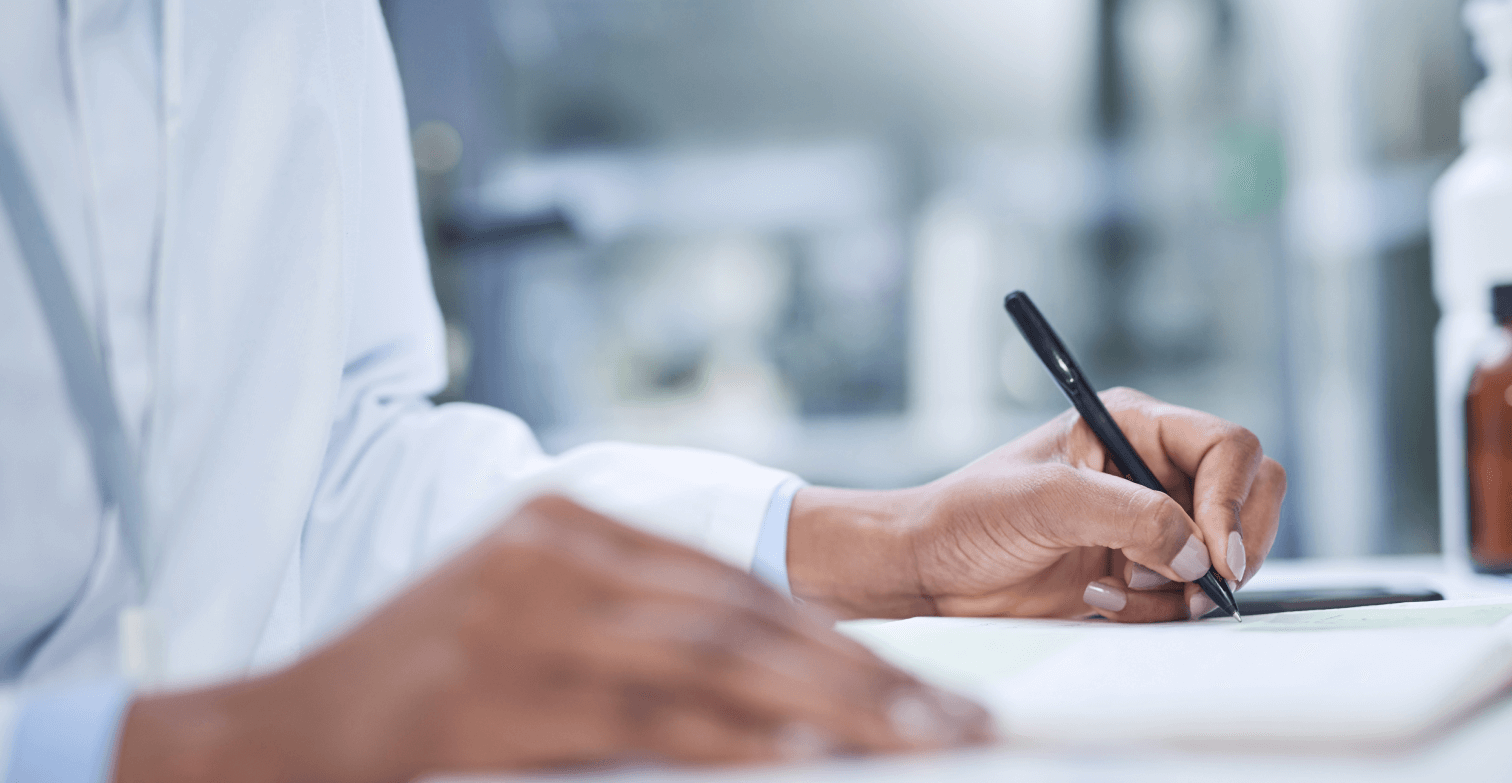 A stock image showing a black woman scientist making manual notes in a lab